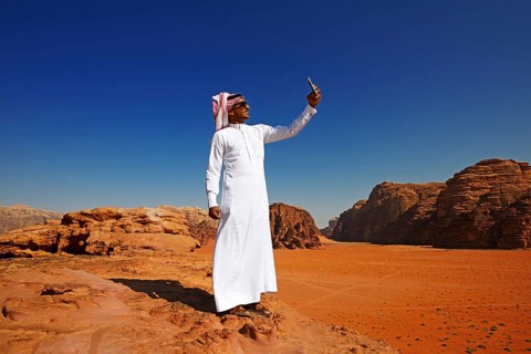 Bedouin uses his smartphone at Rock Arch