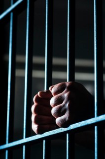 Hands grasping bars in jail