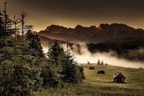 Small cabin on mountain meadow at forest edge