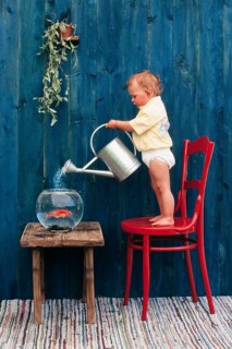 Three year-old girl pouring water in a goldfish bowl