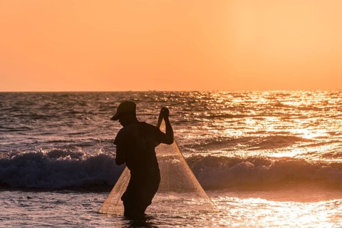 Local fishermen with fishing net in backlight