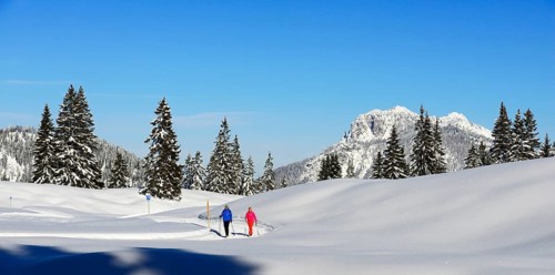 Two hikers walk through snow-covered mountain scenery