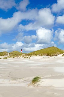 Dunes with lighthouse and cloudy sky