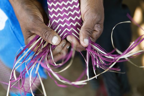 Hands of a woman weaving a mat