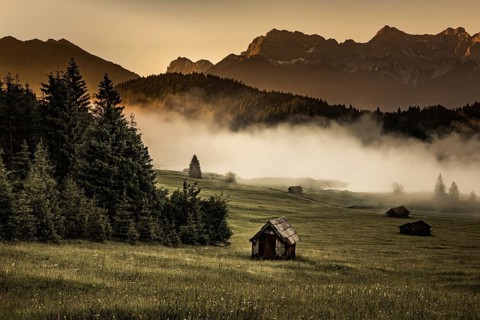 Small cabin on mountain meadow at forest edge