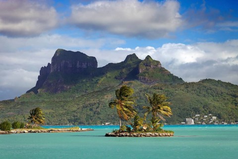 Small palm island in the sea in front of Mont Otemanu