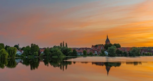 Cityscape with St. Nicholas' Church and lake Schulsee at sunset