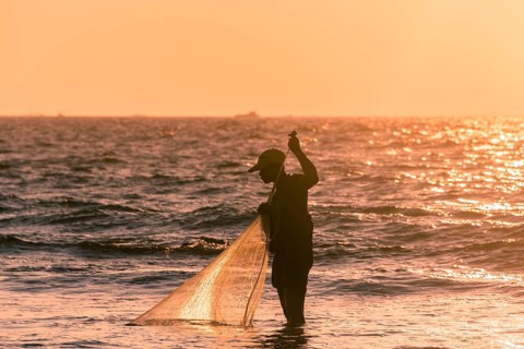 Local fishermen with fishing net in backlight