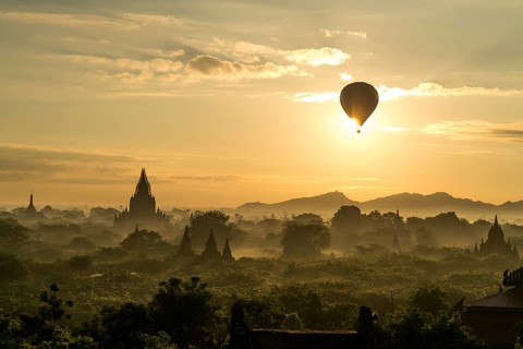 Hot air balloon at sunrise over temples and pagodas