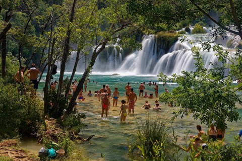 Tourists bathe at the waterfall Smotorcycleinski Buk