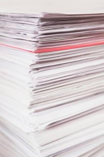 Pile of stacked white paper reports with red one sticking out