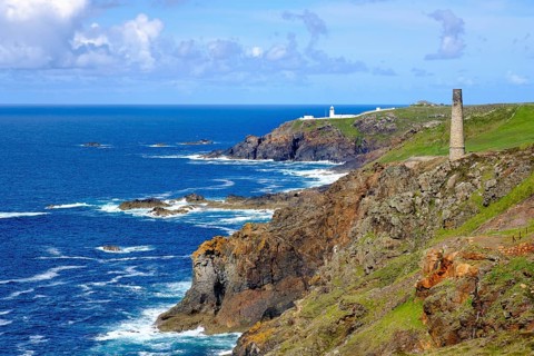 Rocky coast with old chimney from the Levant Mine and Pendeen Lighthouse