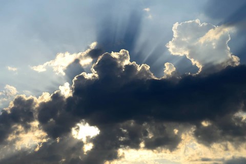 Sun shining behind dark clouds