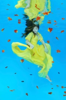 Young woman in yellow dress posing under water