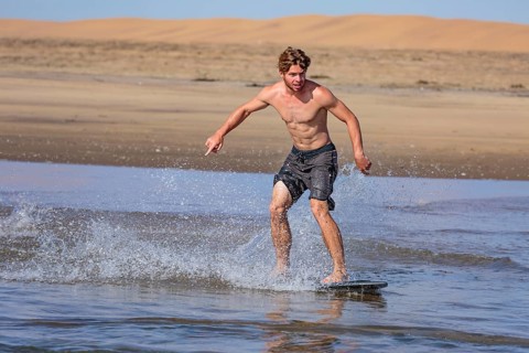 Young man skimboarding in the sea