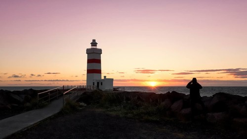 Man photographs sunset at lighthouse in Garour