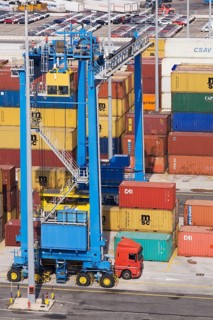Top view of terminal with blue gantry crane loading truck with shipping container