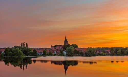 Cityscape with St. Nicholas' Church and lake Schulsee at sunset