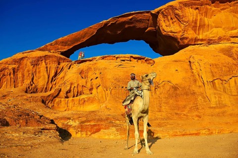 Bedouin rides his camel at Rock-Arch Al Kharza