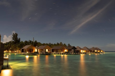 Wooden huts on stilts in lagoon at night