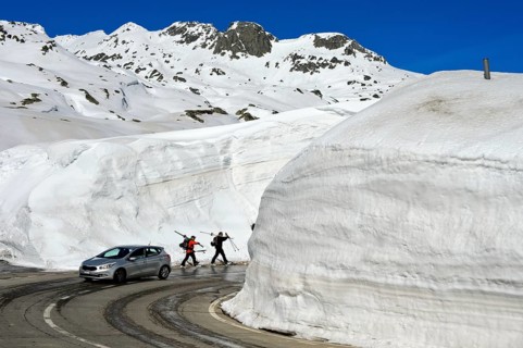 Car and two skiers in front of high snow walls