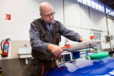 Coachbuilder master with the polishing machine on the car