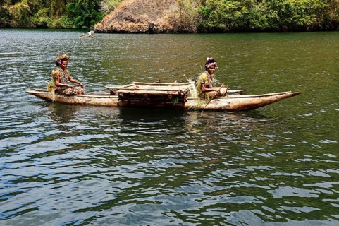 Korafe girls paddling in a dugout canoe with outrigger