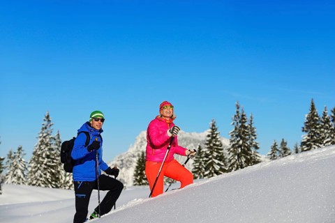 Two hikers walk through deep snow
