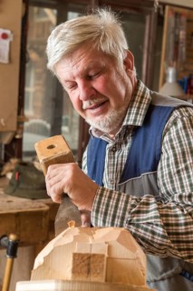 Wooden mask carver using wood carving tools on a wooden block
