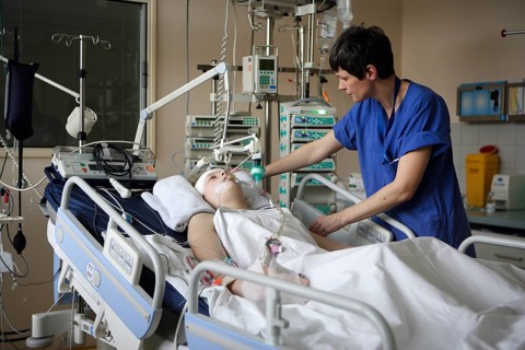 Child in hospital bed is attended by intensive care nurse