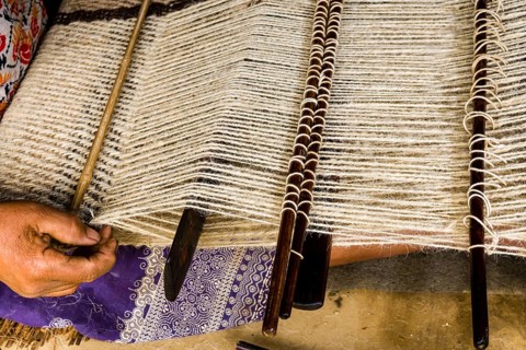 Native woman weaving blanket using sheep's wool