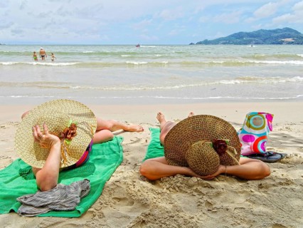 Women with large sun hats sunbathing on the beach