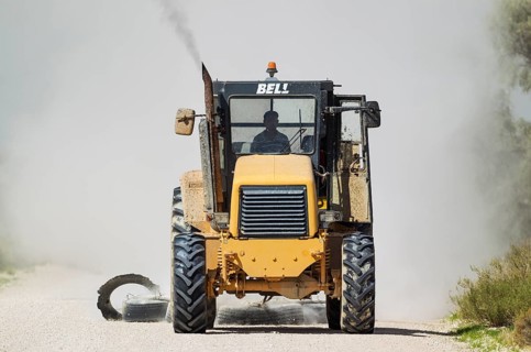 A tractor pulling tyres for grading the parks gravel roads