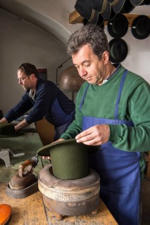 Hatter holding dry wool felt hat in an edge mold