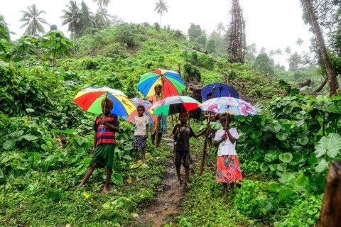 Native women with children with colourful umbrellas in the rain in the village of Rangsuksuk
