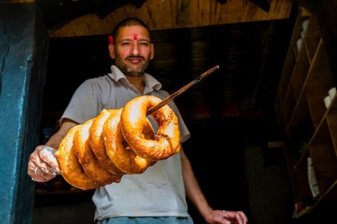 Salesman is displaying some fresh doughnuts on a wooden stick