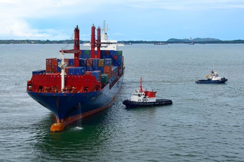 Container ship and pilot vessels berthing in the harbor