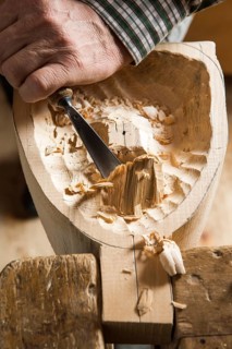 Carving the backside of a wooden mask using wood carving tools