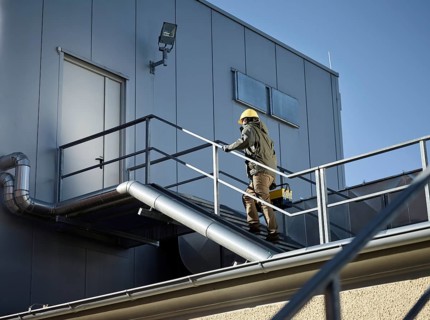 Engineer with yellow helmet and tool box using a staircase to an engine room