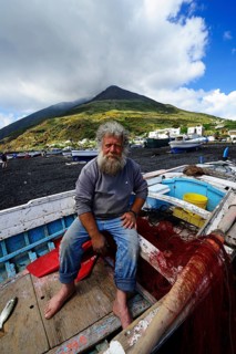 Fisherman in his boat in front of volcano on Scari beach
