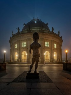 Bodemuseum on the Museum Island with the bronze sculpture Hektor by Markus Lupertz at fog in dusk