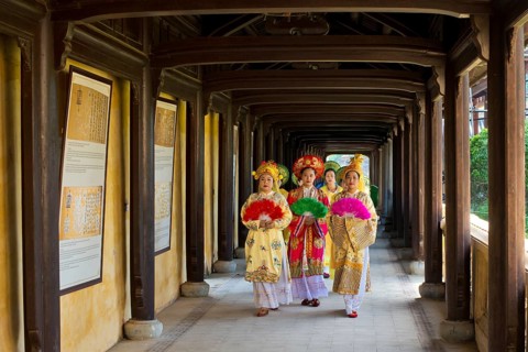 Vietnamese extras in traditional robes walking through imperial palace Hoang Thanh