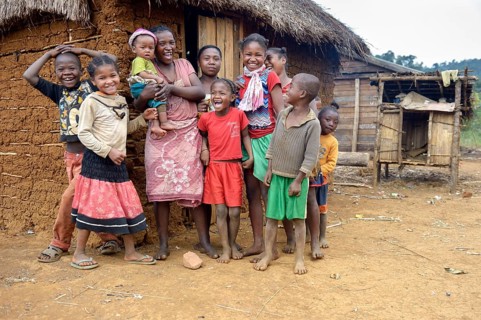 Laughing women and children in front of hut