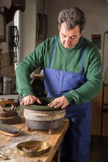 Hatter pushing dry wool felt hat into edge mold