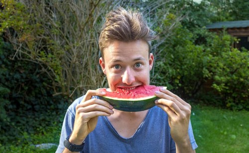 Young man eating a melon