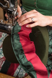 Hands sewing inner lining on a wool felt hat