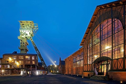 Illuminated machine hall with headframe at dusk