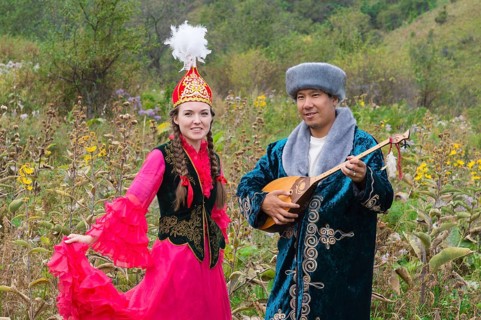 Kazakh man singing and playing the dombra for a woman