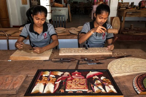 Native Sinhalese girls carving traditional wooden pictures