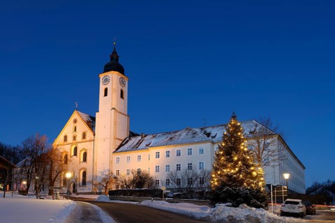 Illuminated Christmas tree in front of monastery church Dietramszell
